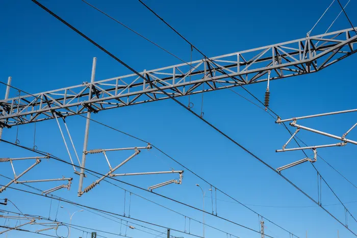 Caténaire et isolateurs d'une ligne ferroviaire électrifiée sur ciel bleu