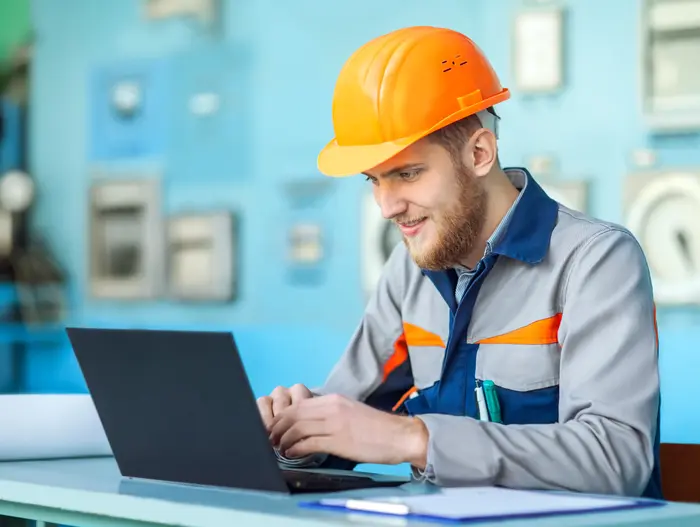 Technicien casqué suivant une formation en ligne sur ordinateur portable